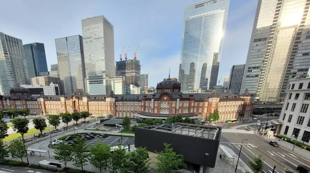 Tokyo Station with surrounding skyscrapers reflecting sunlight, symbolizing tradition and modern business culture in Japan.